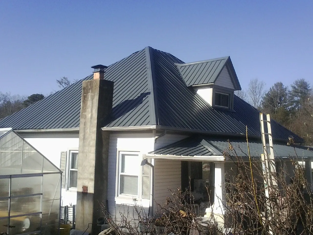 Dark blue standing seam metal roof on a white farmhouse with dormer — Slate & Tile Roof Repair by Roofing Brothers in Nauvoo
