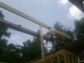 Carpenter setting a ridge beam over a new addition frame — Ice Dam Removal by Roofing Brothers in Nauvoo