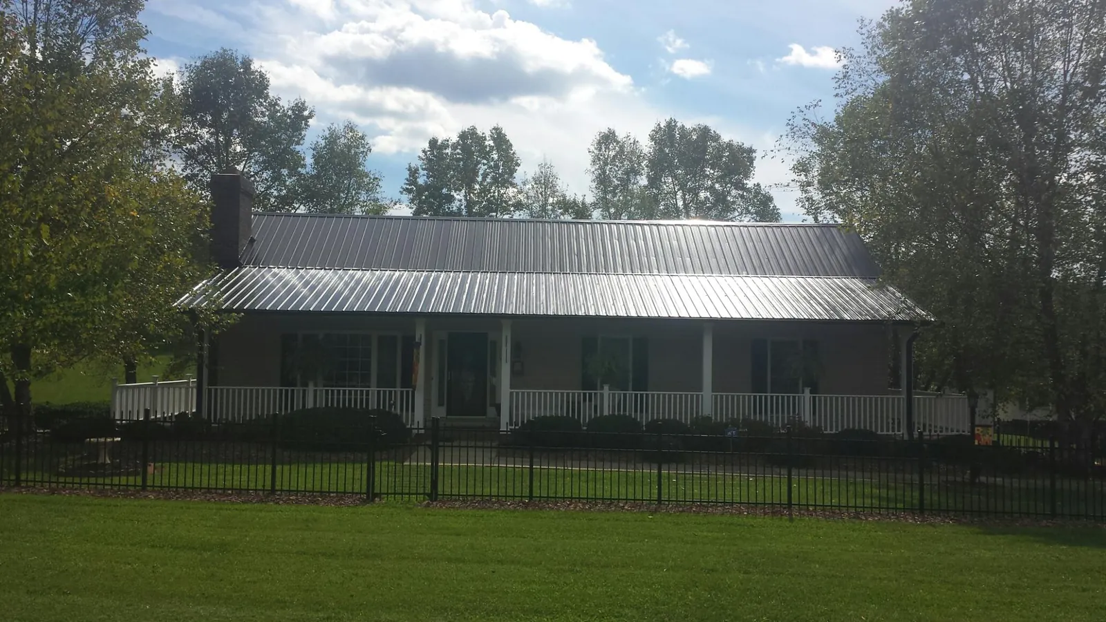 Gray metal roof on a brick ranch with a full width front porch — Gutter Guard Installation work by our crew in Nauvoo