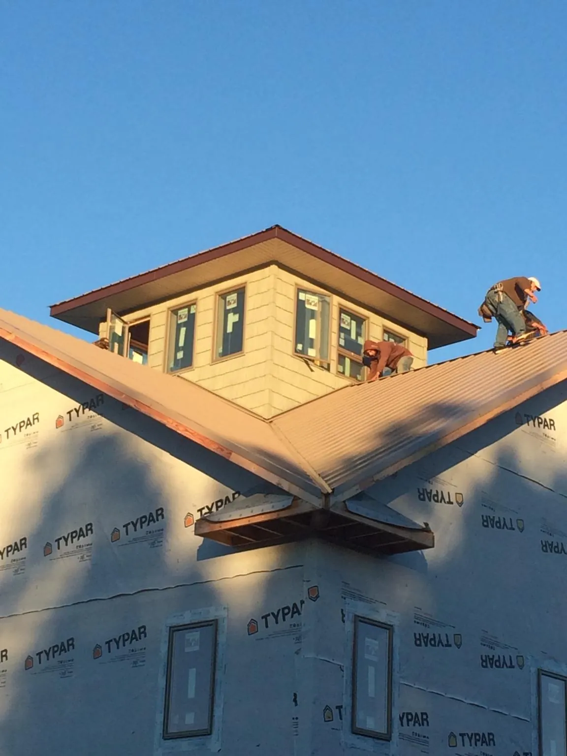 Roofers working around a rooftop cupola on a new metal roof at sunset — Roof Waterproofing in Nauvoo by Roofing Brothers